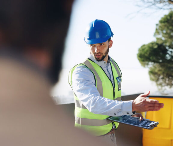 Engineer, man and clipboard for solar power at construction site with business people, point and talk. Person, technician and outdoor for presentation, renewable energy solution and sustainability