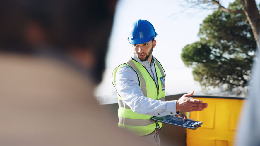 Engineer, man and clipboard for solar power at construction site with business people, point and talk. Person, technician and outdoor for presentation, renewable energy solution and sustainability
