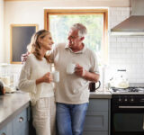 Senior, couple and drinking coffee with a love, marriage and happiness morning mindset at home. Happy smile and hug of a elderly woman and man with tea in a house kitchen together with quality time