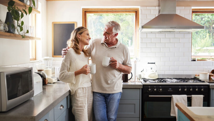 Senior, couple and drinking coffee with a love, marriage and happiness morning mindset at home. Happy smile and hug of a elderly woman and man with tea in a house kitchen together with quality time