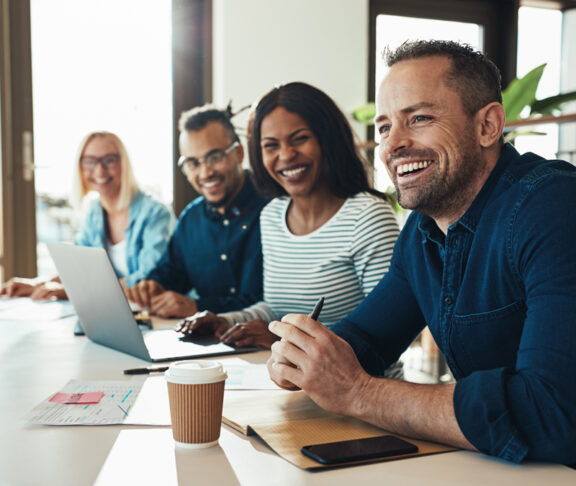 Diverse office colleagues laughing together during a meeting