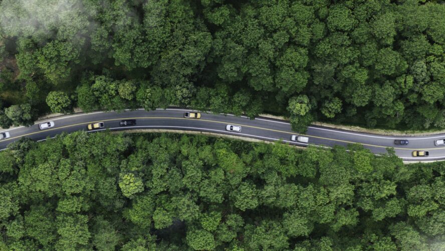car on road midst forest and natural. Environmental friendly travel. Sustainable transportation and green logistic to Net zero carbon emission for Save earth.