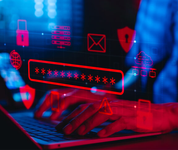 Osoba wpisująca hasło na laptopie, otoczona cyfrowymi ikonami bezpieczeństwa w cyberprzestrzeń