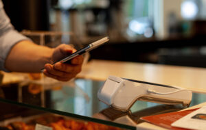 Cyfryzacja płatności – klient płaci smartfonem zbliżeniowo przy terminalu w sklepie