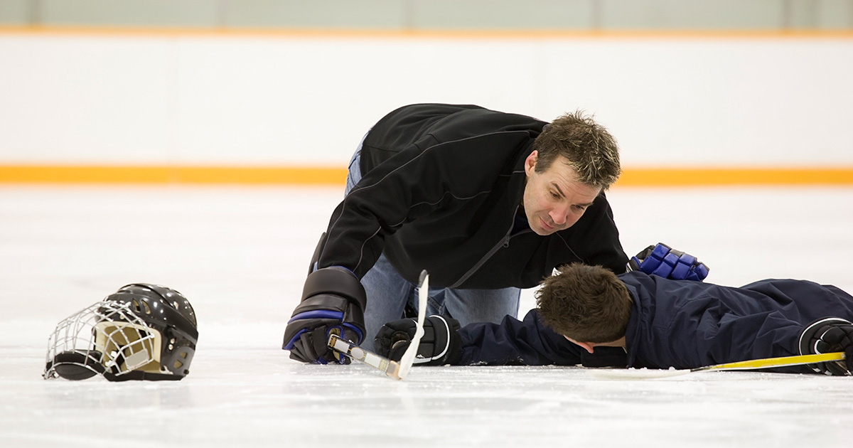 Peewee hockey player receiving help after an injury
