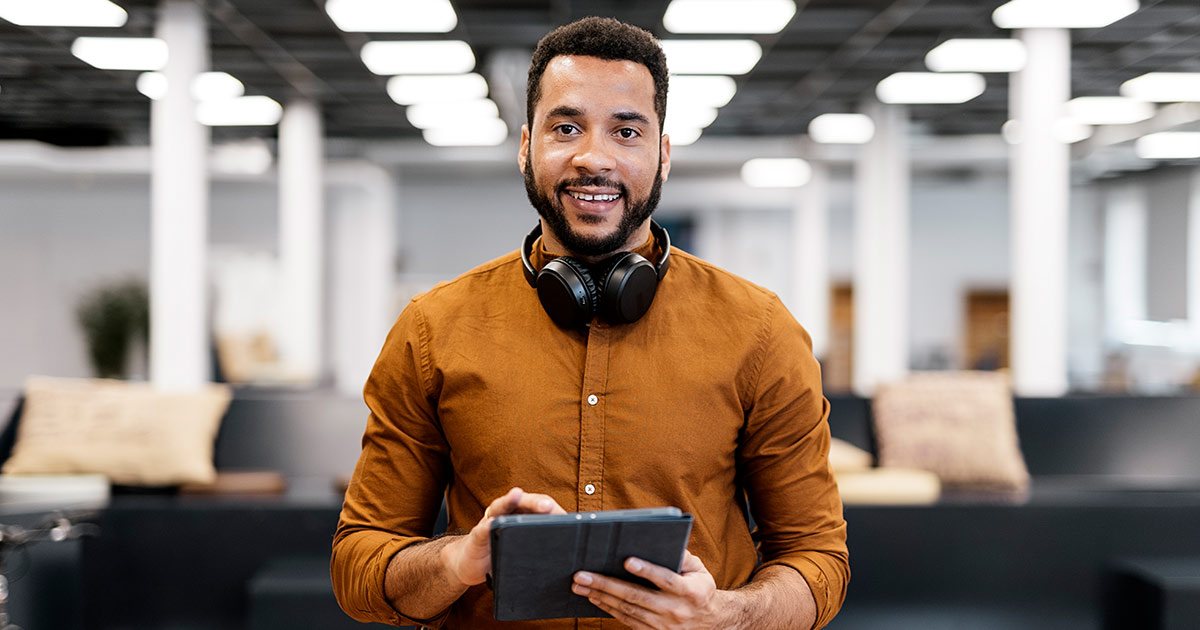 Man in an office smiling and holding a digital tablet
