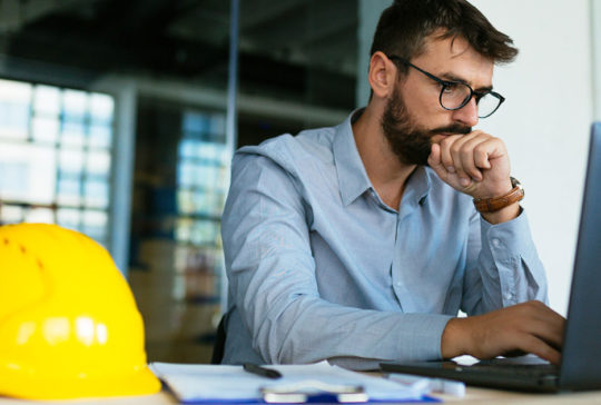 man with beard and glasses working on computer