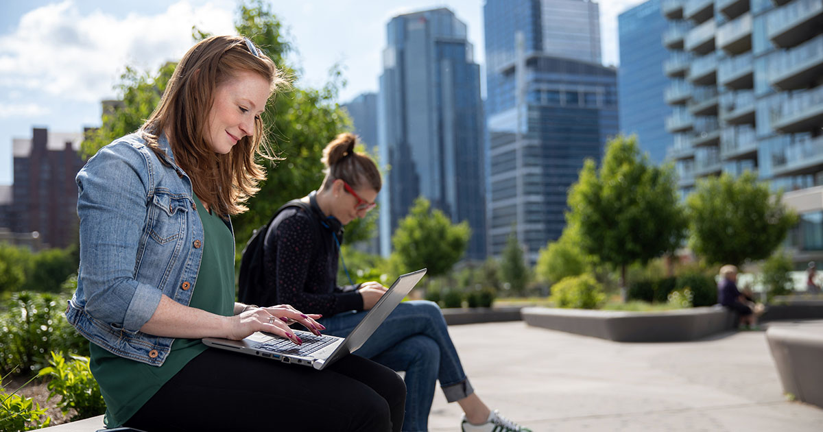 sait young woman on computer in campus