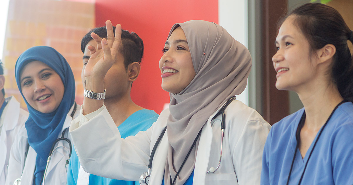 Hijabi doctor smiling and raising her hand