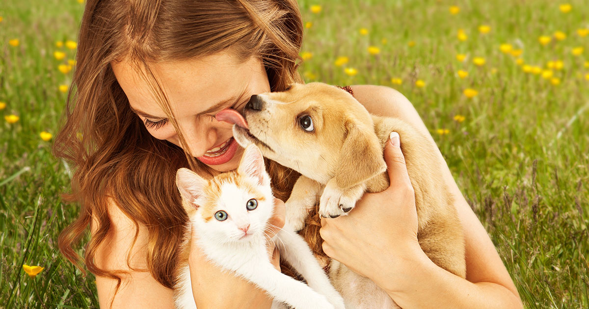 Woman holding a puppy and a kitten