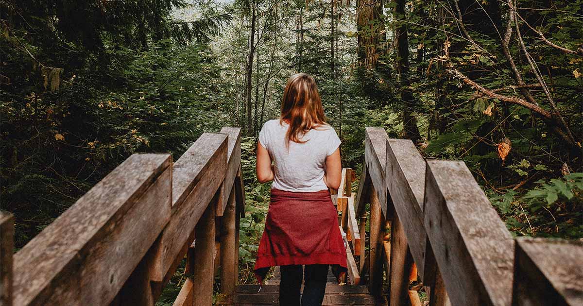 woman walking down a path amid nature