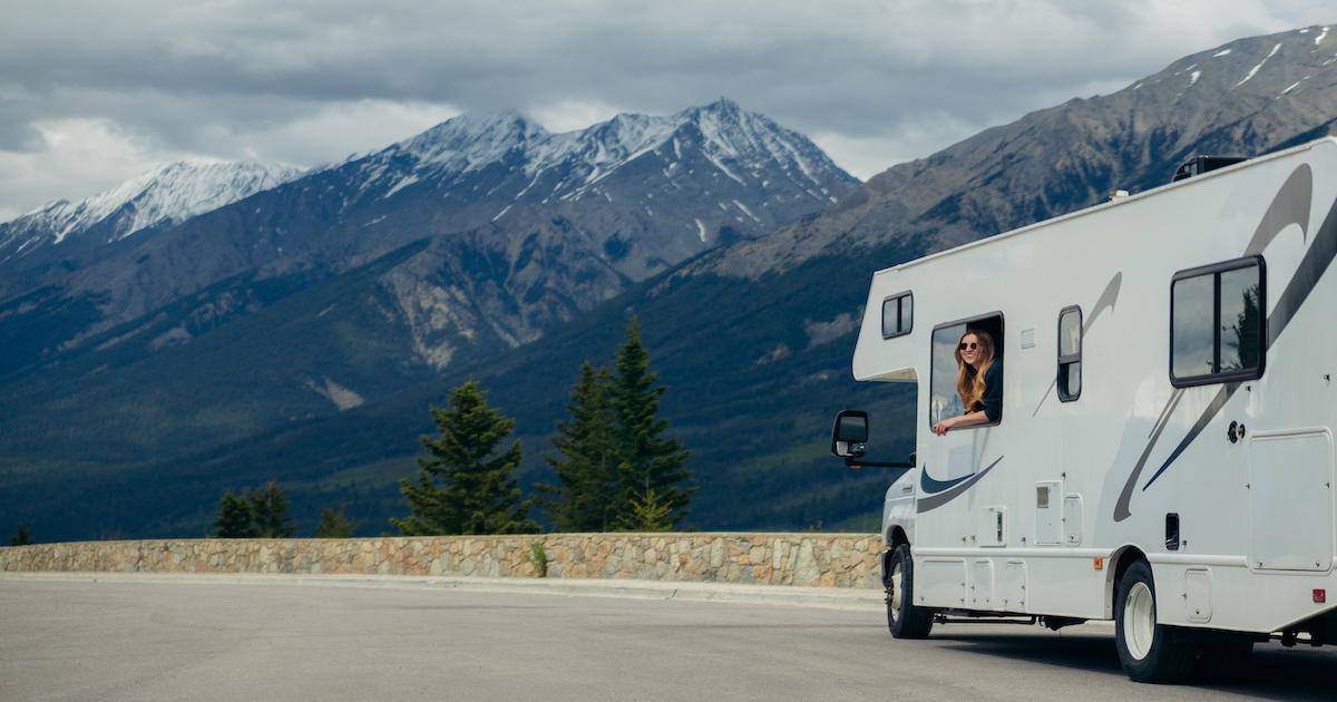 Woman leaning out of RV with mountains in the background