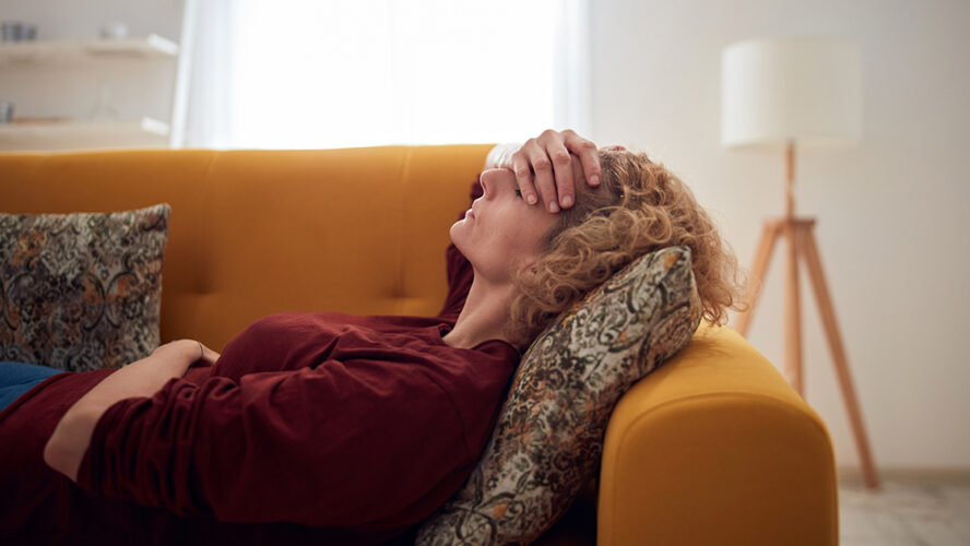 Woman with sinus pain, headache and stomach problems, lying on a couch at home