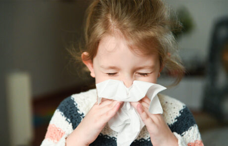little girl blowing her nose and covering it with handkerchief with eyes closed