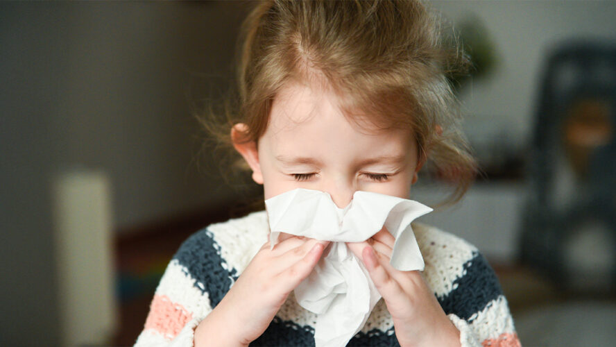 little girl blowing her nose and covering it with handkerchief with eyes closed