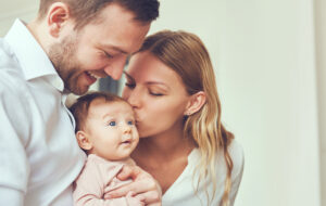 couple parents kissing their newborn