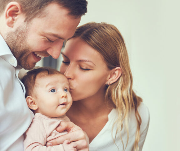 couple parents kissing their newborn