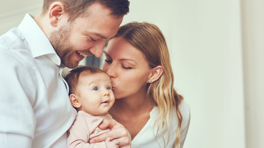 couple parents kissing their newborn