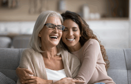 Fröhlich aufgeregt Mutter und erwachsene Tochter Frau, die sich zu Hause amüsiert, mit Kopf berühren, auf dem Sofa sitzen, mit geschlossenen Augen lachen, lustiges Gespräch genießen, Freizeit, Familienaffektion