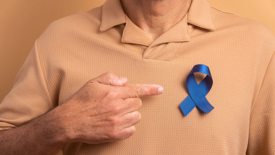 Detailhände eines älteren Mannes, der ein blaues Band auf beigem Studiohintergrund zeigt. Prostatakrebs, Bewusstseinskonzept.