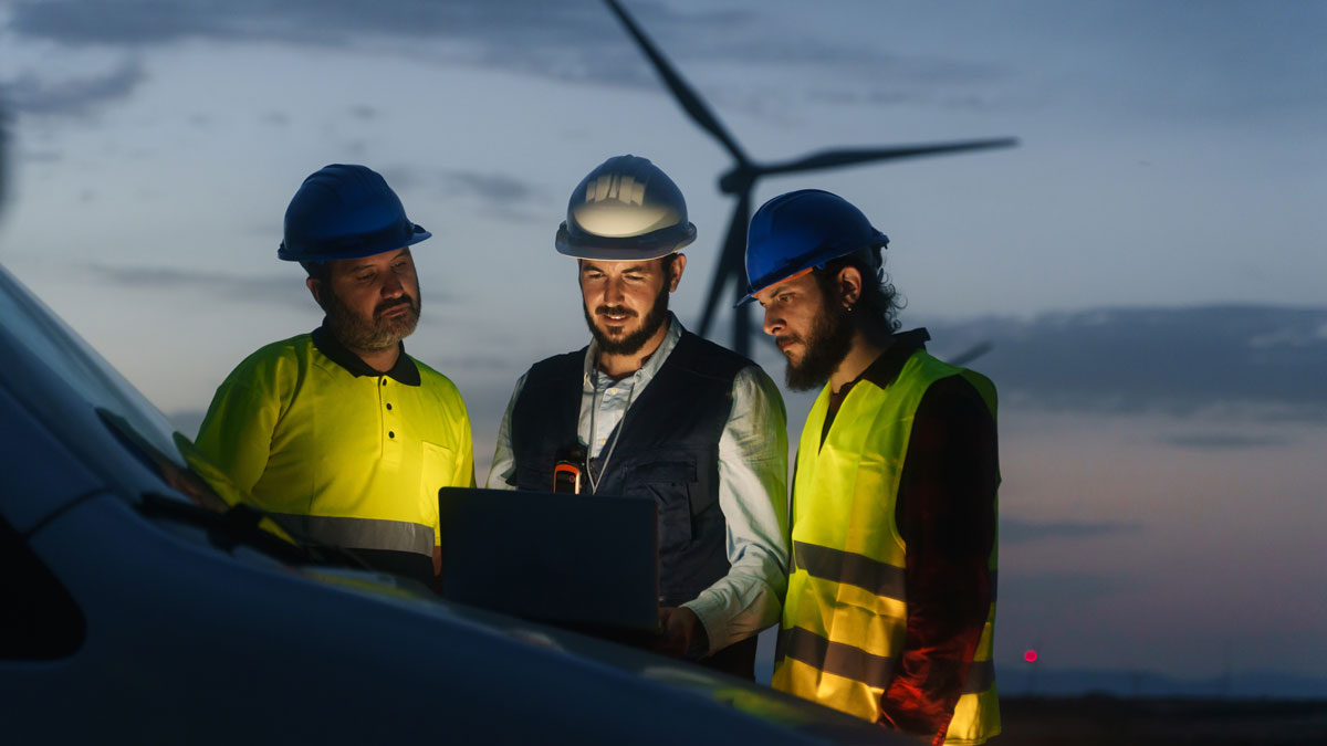 Electrical Engineer and technical industry workers discussing project of electricity wind power station, planing renewable energy factory at night