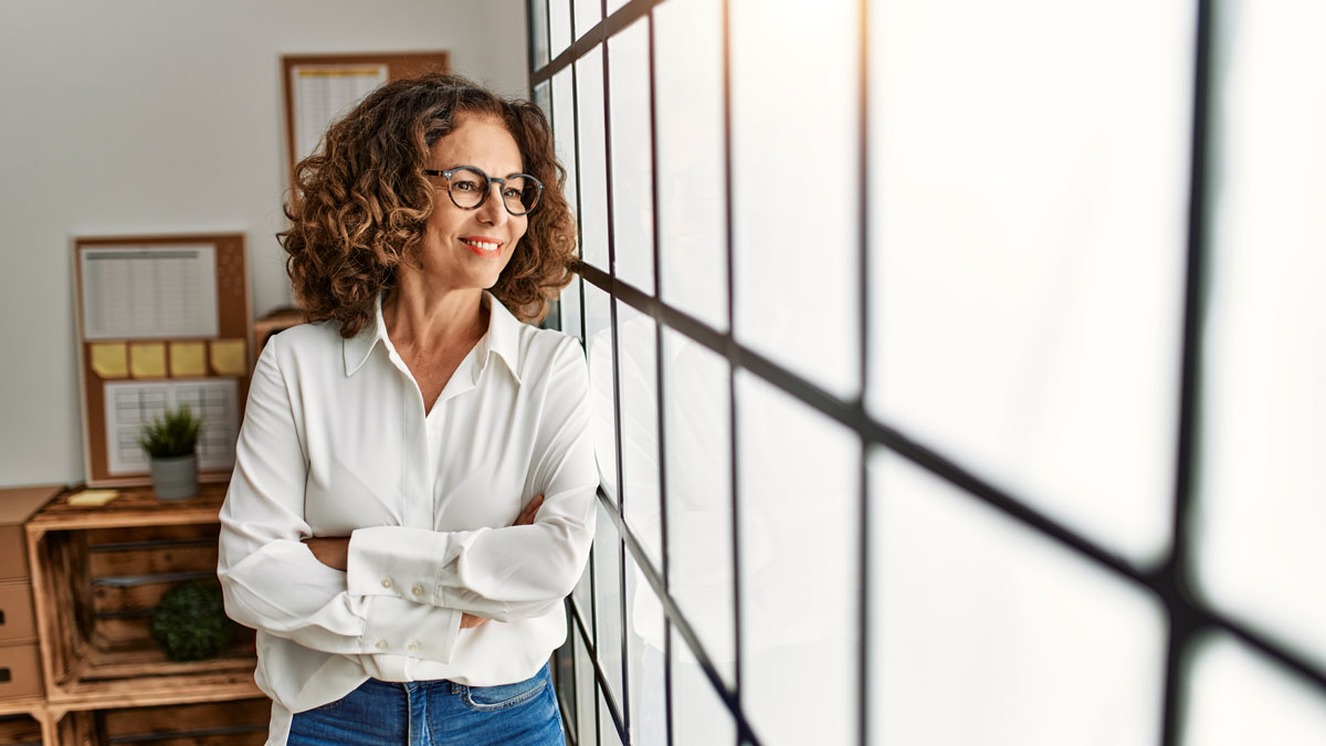 Middle age hispanic woman smiling confident with arms crossed gesture at office