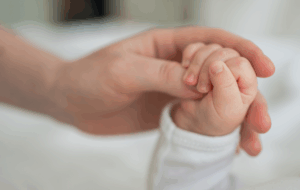 Glückliche Familie. Winziges Neugeborenes Baby kleine Hand auf der Mutterhand Handfläche. Neugeborenes Baby, das nach der Geburt den Elternfinger hält. Mutter Baby zu Hause. Unterstützung des Schutzes eines neuen Lebens. Sorgfältig handhaben