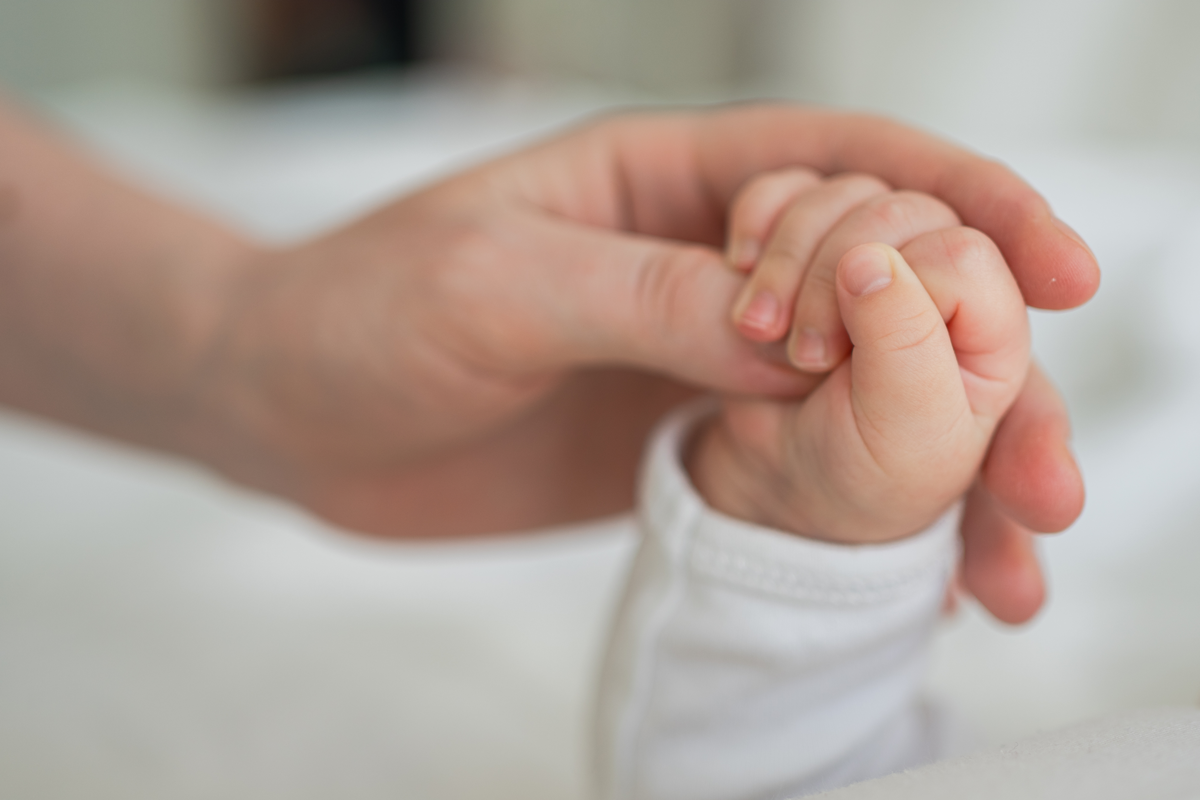 Glückliche Familie. Winziges Neugeborenes Baby kleine Hand auf der Mutterhand Handfläche. Neugeborenes Baby, das nach der Geburt den Elternfinger hält. Mutter Baby zu Hause. Unterstützung des Schutzes eines neuen Lebens. Sorgfältig handhaben