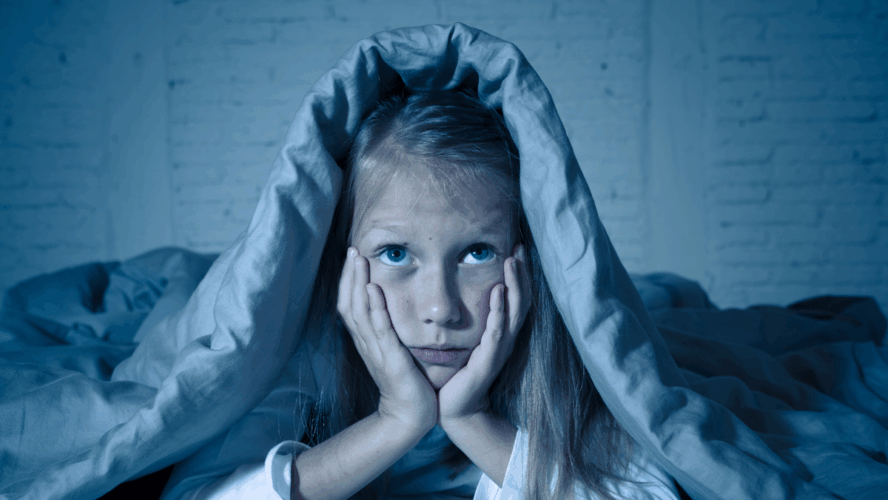 Das süße kleine, kaukasische Mädchen, das im Bett liegt und mit einer Decke bedeckt ist, die sich erschöpft und schlaflos an Schlaflosigkeit Depression Leid in Kinder Emotionale und Schlafstörungen Konzept.