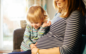 Pregnant mother sitting on sofa with child