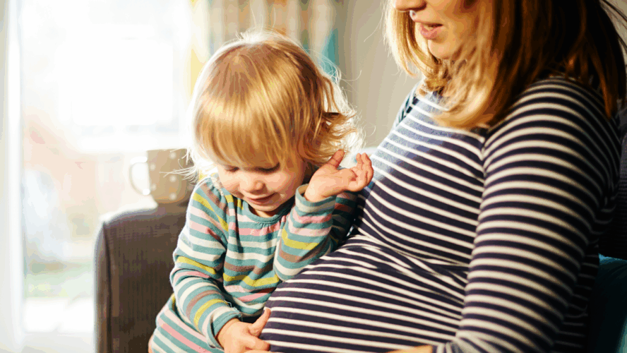Pregnant mother sitting on sofa with child