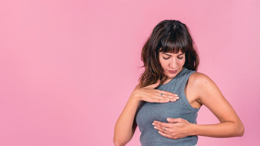 Frau, die eine Brust-Selbstprüfung auf rosafarbenem Hintergrund durchführt. Leerzeichen kopieren