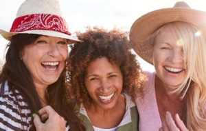 tre leende kvinner i solen