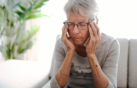 Eine unglückliche Kopfschmerzen, ermüdete Senderin sitzend auf Sofa zu Hause