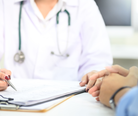 Nahaufnahme der ärztlichen Beratung mit dem Patienten, Hinweis auf medizinische Dokumente während der Untersuchung.