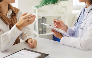 Zugeschnittene Ansicht des weiblichen Arztes aufmerksam zuhören Frau Patientin und Notizen während der Beratung. Arzt oder Kardiologe, der sich auf das Verständnis und die Behandlung von Fragen der Patientengesundheit konzentriert.