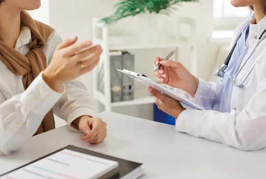 Zugeschnittene Ansicht des weiblichen Arztes aufmerksam zuhören Frau Patientin und Notizen während der Beratung. Arzt oder Kardiologe, der sich auf das Verständnis und die Behandlung von Fragen der Patientengesundheit konzentriert.