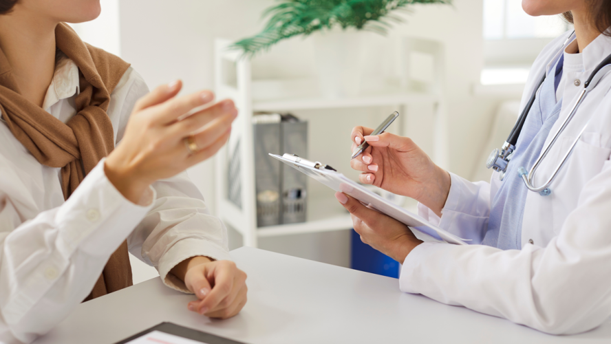 Zugeschnittene Ansicht des weiblichen Arztes aufmerksam zuhören Frau Patientin und Notizen während der Beratung. Arzt oder Kardiologe, der sich auf das Verständnis und die Behandlung von Fragen der Patientengesundheit konzentriert.