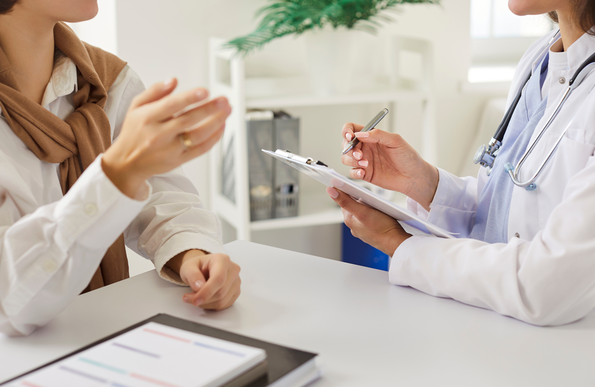 Zugeschnittene Ansicht des weiblichen Arztes aufmerksam zuhören Frau Patientin und Notizen während der Beratung. Arzt oder Kardiologe, der sich auf das Verständnis und die Behandlung von Fragen der Patientengesundheit konzentriert.