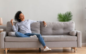 African young relaxed woman sitting on couch breathing fresh air