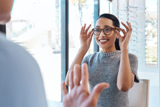 A customer buying, testing or trying on glasses at an optometrist store or shop. Health care eye wear professional picking or selling a pair of new eyeglasses to a young female client or patient