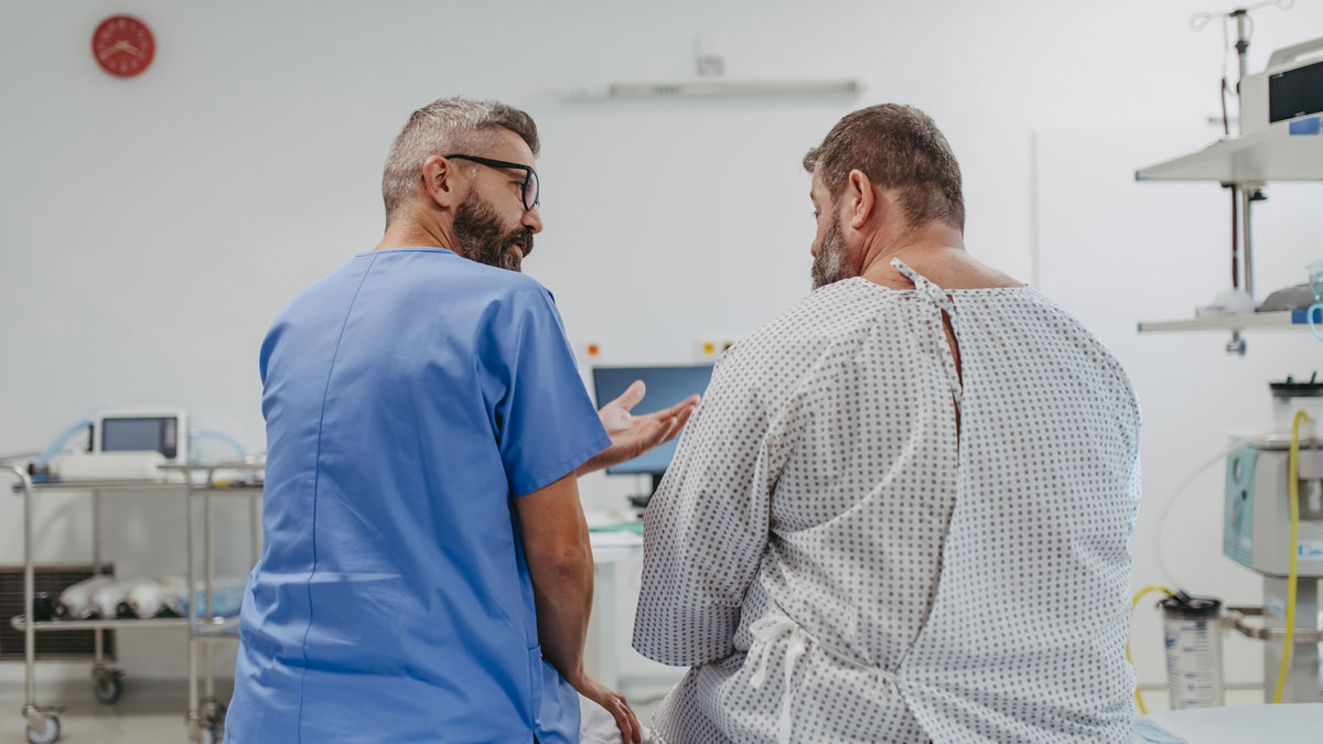 Supportive doctor soothing a worried overweight patient, discussing test result in emergency room. Illnesses and diseases in middle-aged men's health. Compassionate physician supporting stressed