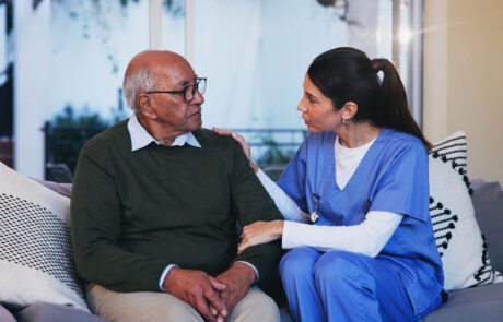 Senior, man and nurse with conversation on sofa for healthcare support, medical advice and consulting. Retirement home, caregiver and old person on couch with assistance, homecare and health service