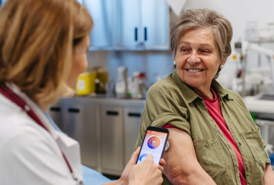 Endocrinologist teaching older patient how to connect continuous glucose monitor with mobil app