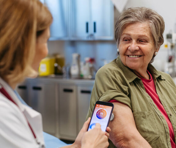 Endocrinologist teaching older patient how to connect continuous glucose monitor with mobil app