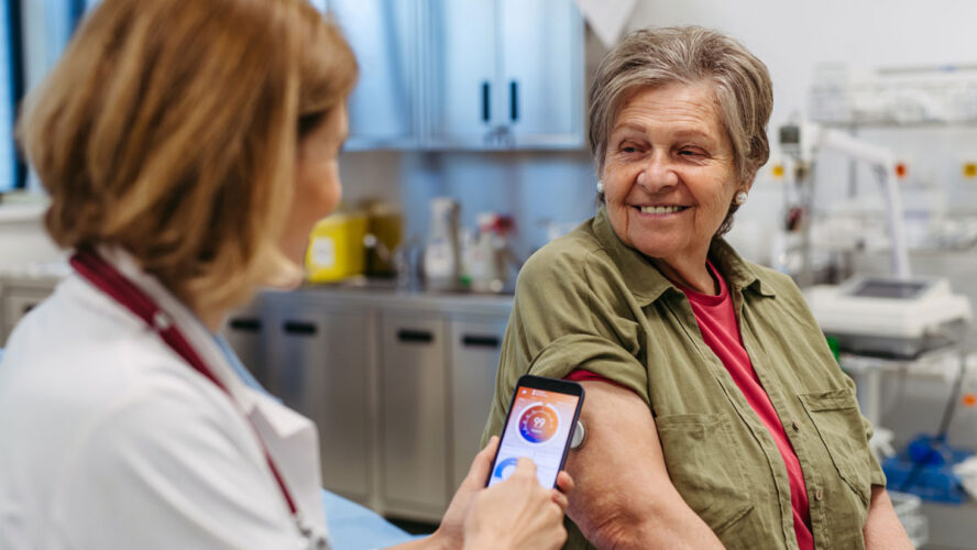 Endocrinologist teaching older patient how to connect continuous glucose monitor with mobil app