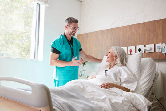 Surgeon Visiting And Talking With Mature Female Patient In Hospital Bed