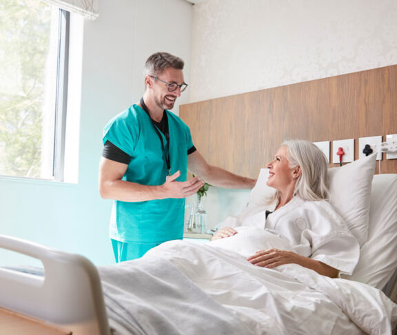 Surgeon Visiting And Talking With Mature Female Patient In Hospital Bed
