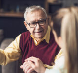 Home doctor is visiting senior man to check his health. Professional caregiver is assisting old man at his home