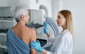 Senior woman having mammography scan at hospital with medical technician. Mammography procedure, breast cancer prevention